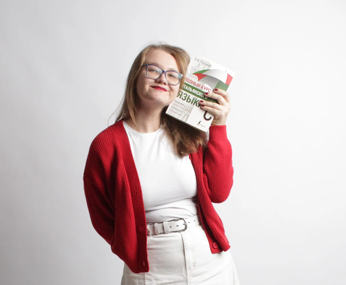 Viktoria Laskina smiling warmly while holding an Italian coursebook to her cheek, with the words "Italian for love".