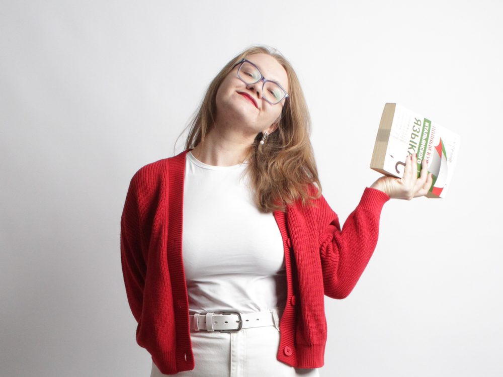Viktoria Laskina holding up an Italian coursebook and smiling.